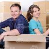 Smiling Young Couple Sitting Back to Back Behind Card Box Stock Photo