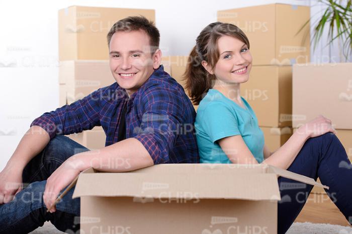 Smiling Young Couple Sitting Back to Back Behind Card Box Stock Photo