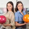 Girls Standing Back To Back At Bowling Alley Stock Photo