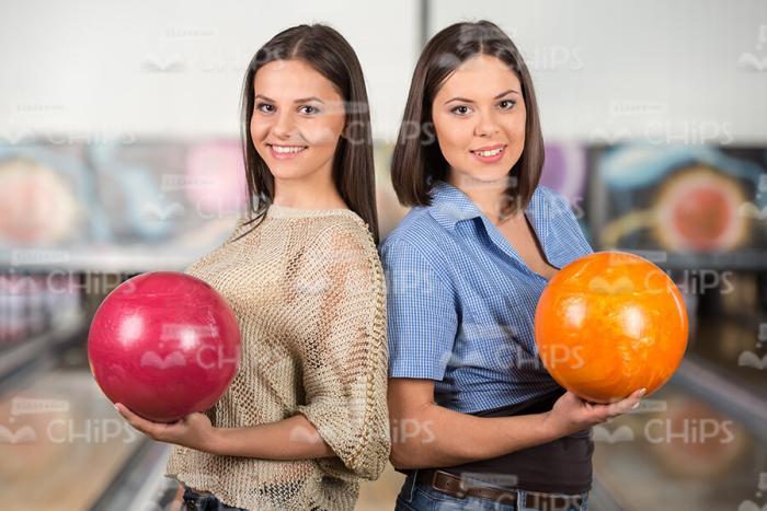 Girls Standing Back To Back At Bowling Alley Stock Photo