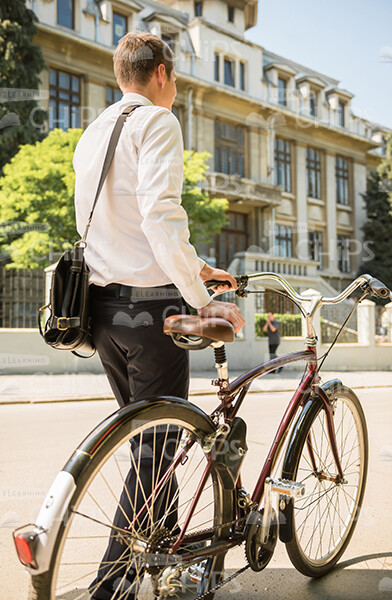 Office Employee Walking With Bicycle Back View Stock Photo