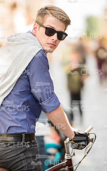 Serious Young Man Turns Back While Rides On Bike Stock Photo