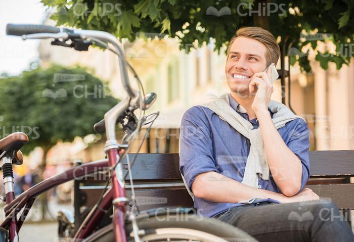 Smiling Young Man Talking On Phone And Looking Into The Distance Stock Photo