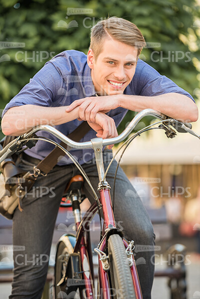 Young Man Smiles And Leans On Bicycle Handlebars Stock Photo