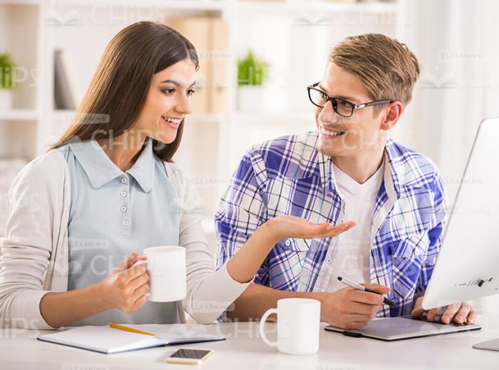 Pretty Girl Pointing At Monitor While Showing Something To Her Friend Stock Photo