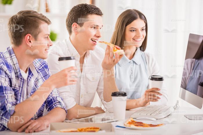Young People Watching Something On Computer While Eating Lunch Stock Photo