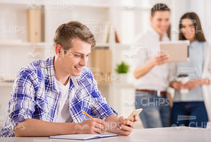 Young Man With Notebook Using Mobile Phone Stock Photo