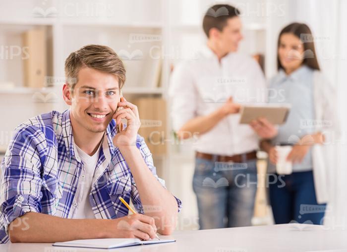 Young Man Talking On Mobile Phone And Making Notes Stock Photo