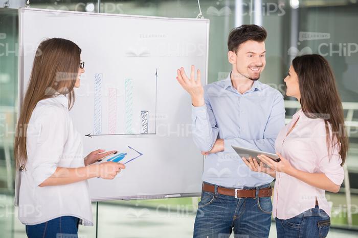 Two Women And Smiling Man Discuss Business Presentation Stock Photo