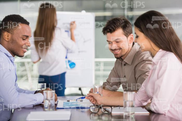 Smiling People Sitting and Discussing New Materials Stock Photo