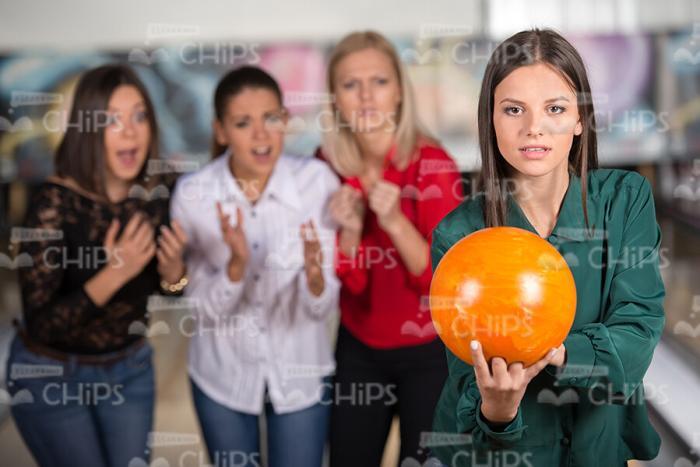Focused Woman In Green Blouse Holds Orange Bowling Ball Stock Photo