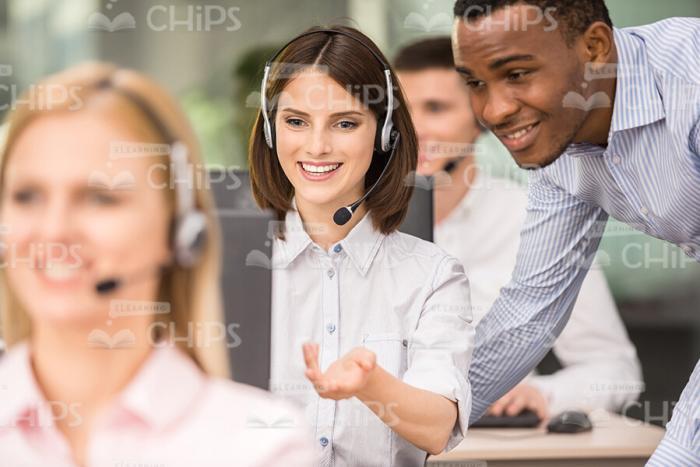 Call Center Operator Showing Something To Colleague Stock Photo