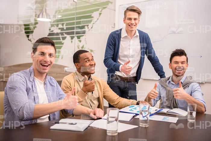 Happy Young Men In Meeting Room Showing Thumbs Up Stock Photo