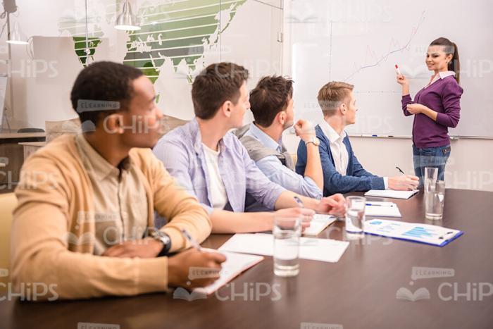 Young Woman Standing At Whiteboard, Drawing Chart And Talking With Audience Stock Photo