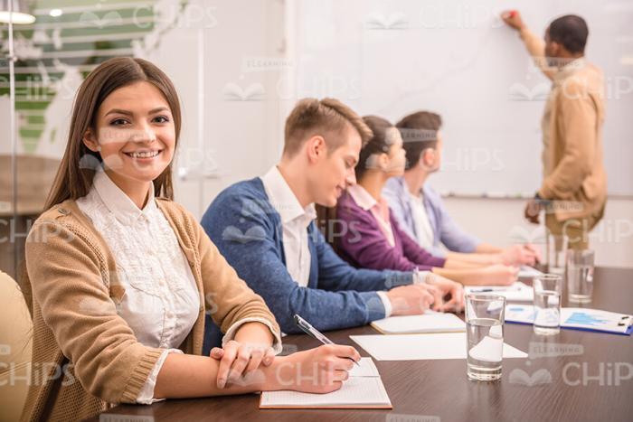 Pretty Woman Sitting At Table And Holding Pen Stock Photo