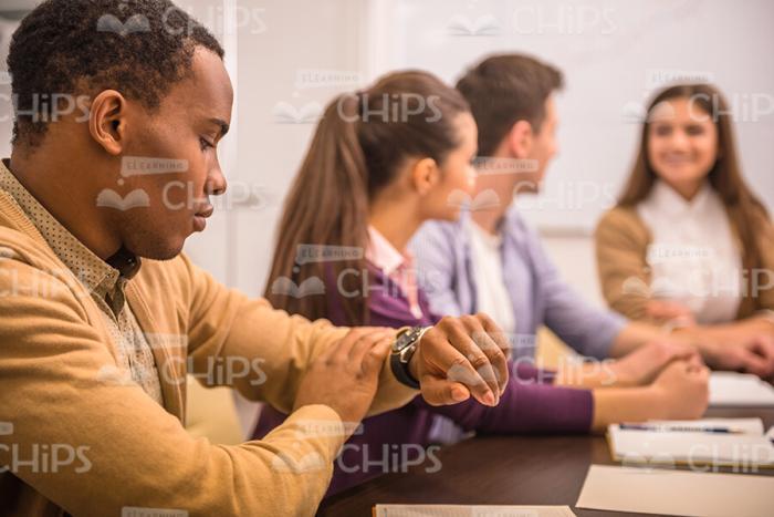 Black Young Man Looks At His Watch Stock Photo
