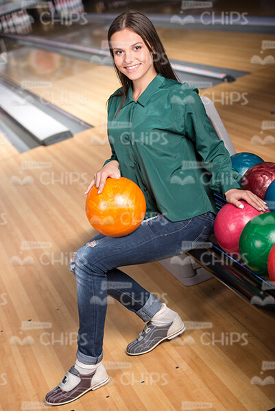 Pretty Young Girl Sits Near The Colored Bowling Balls Stock Photo
