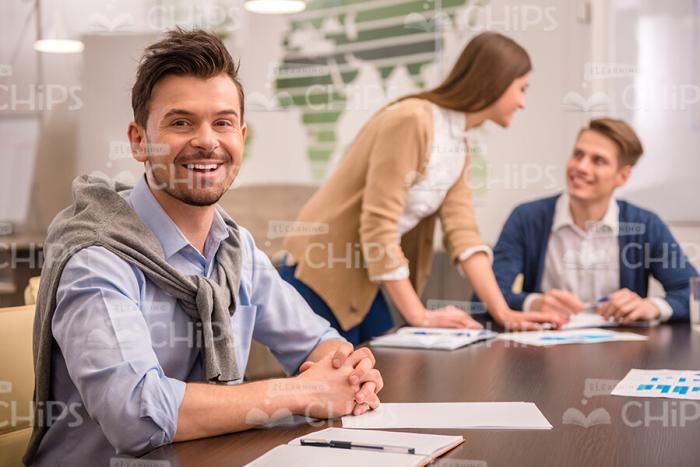 Smiling Man Sits Behind Table with His Hands Locked Stock Photo