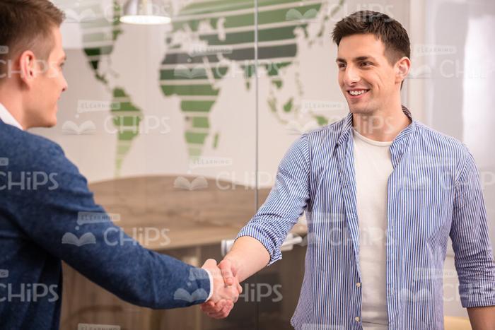 Glad Young Man Shakes Hands With Colleague Stock Photo