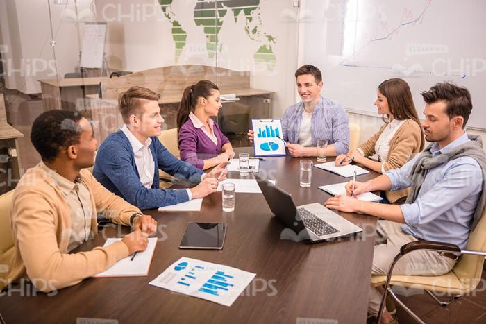 Young Man Presenting Chart To Colleagues Stock Photo