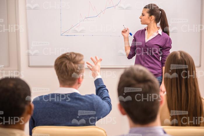 Young Man Pointing On Whiteboard And Saying Something To Female Narrator Stock Photo