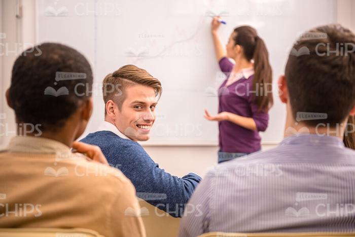Smiling Man Sitting At Conference And Turns To Camera Stock Photo