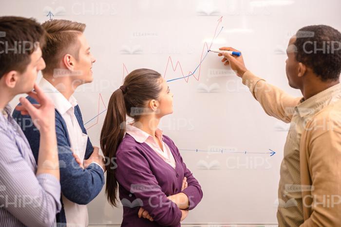 Young Man Writing On Whiteboard And Showing To Students Stock Photo