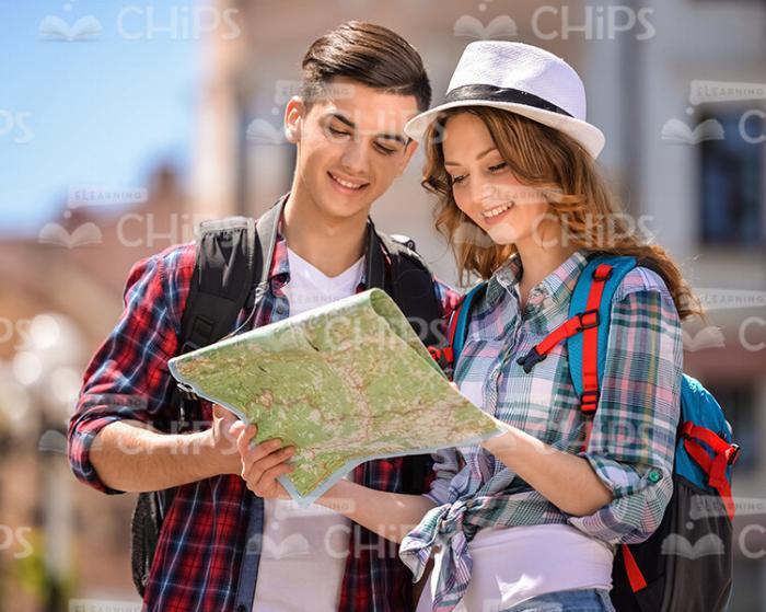 Cheerful Young Tourists Looking At Map Stock Photo