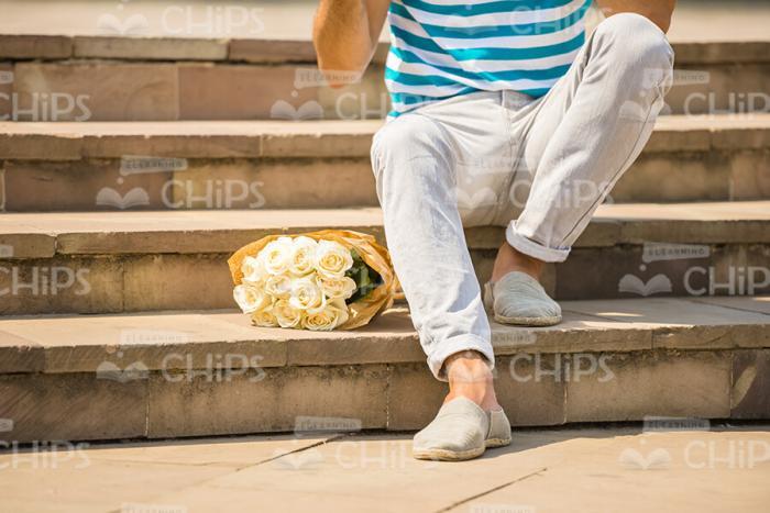 Man With Bouquet Sitting On Stairs Stock Photo