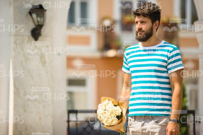 Sad Young Man With Bouquet Waiting For Someone Stock Photo