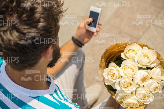 Man With Bouquet Using Mobile Phone Stock Photo