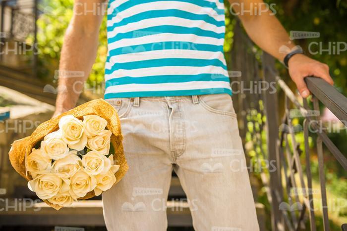 Man In Stripped T-Shirt Holding Bouquet Stock Photo