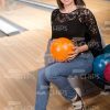 Glad Young Woman Sits Near The Bowling Balls Stock Photo