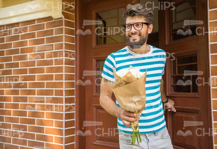 Smiling Bearded Man With Bouquet Going Out From Building Stock Photo