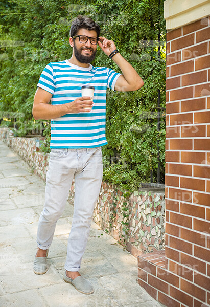 Bearded Man With Coffee Cup And Mobile Phone Walking Down The Street Stock Photo