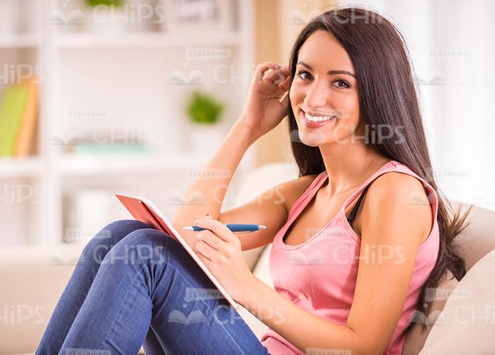 Nice Woman Smiles And Makes Notes Stock Photo