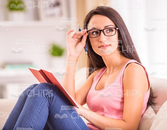 Young Woman Wearing Glasses While Sitting On Sofa Stock Photo