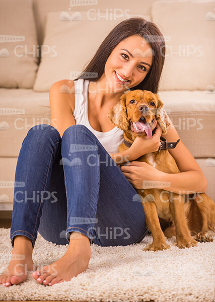Young Woman Sitting On Floor And Hugging Puppy Stock Photo
