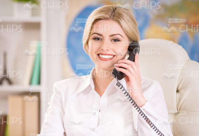 Glad Woman Holding Handset While Talking On Phone Stock Photo