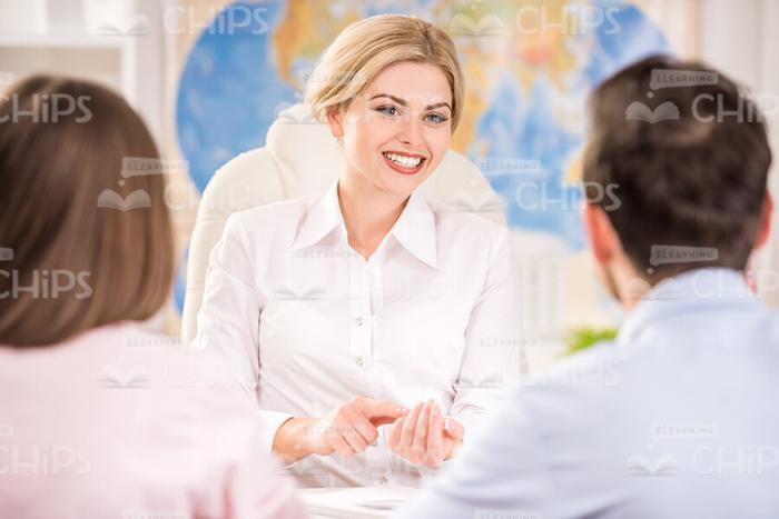 Businesswoman Talking With Clients At Travel Agency Stock Photo