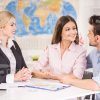 Young Couple Talking To Each Other While Manager Waiting For Their Decision Stock Photo