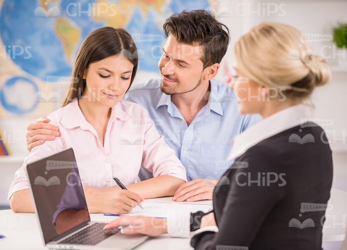 Young Lady Signing Papers And Her Boyfriend Hugs Her Stock Photo