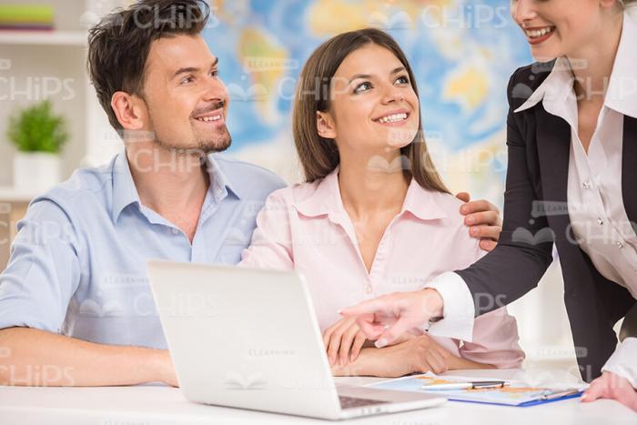 Handsome Young Couple Listening To Travel Agent's Offer Stock Photo