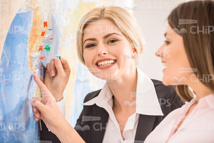 Young Woman Pointing On Map At Travel Agency Stock Photo