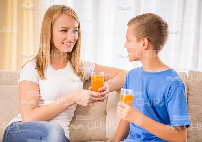 Young Boy And His Mother Sit On Sofa And Drink Juice Stock Photo