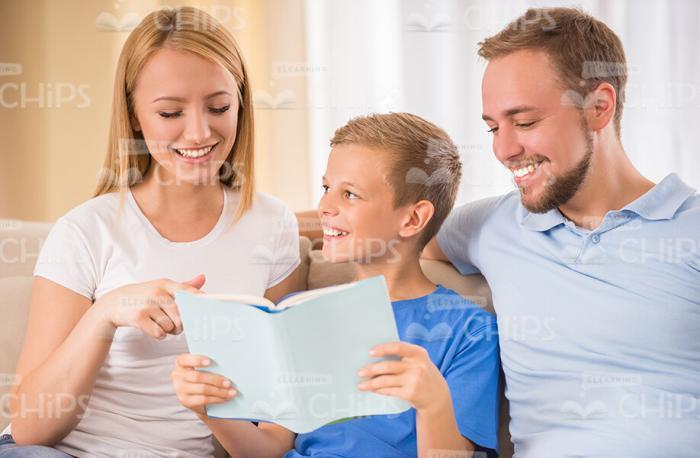 Happy Family Reading Book At Home Stock Photo