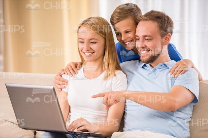 Family Using Laptop And Young Father Pointing On Its Display Stock Photo