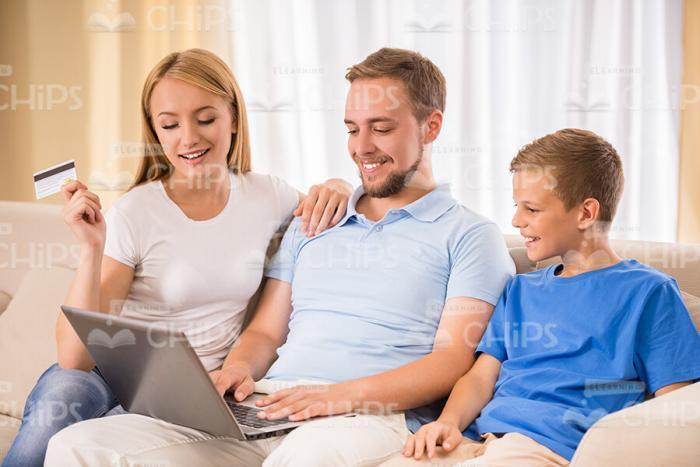 Happy Family Sitting On Sofa And Man Is Typing Text On Laptop Stock Photo