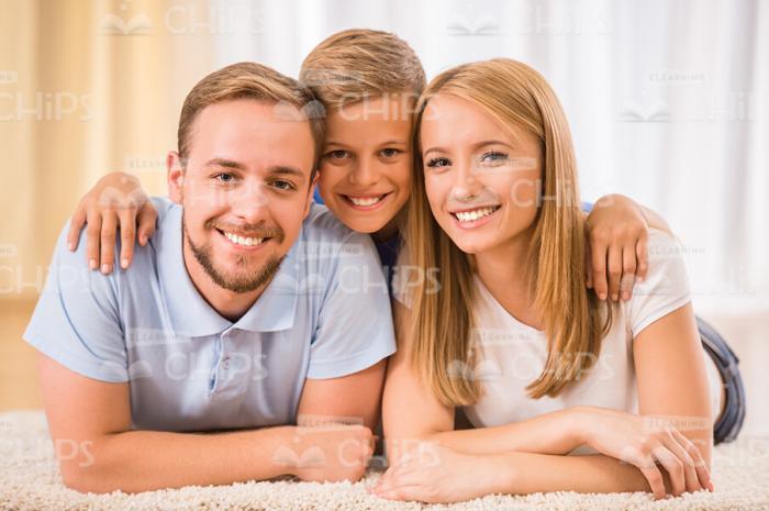 Little Boy With His Parents Lying On Carpet Stock Photo