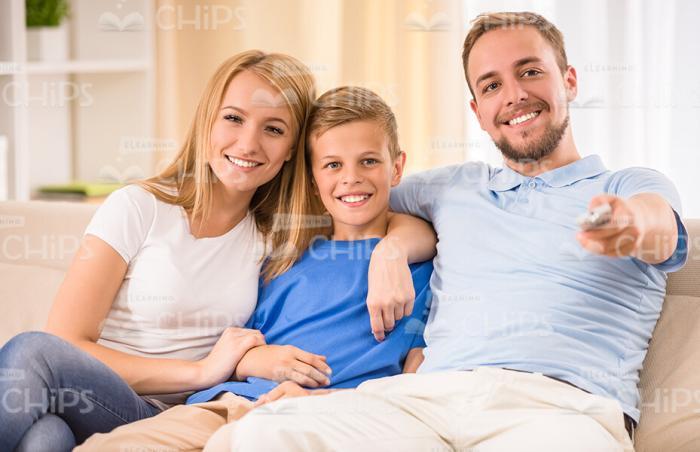 Smiling Young Family Resting At Home And Watching TV Stock Photo